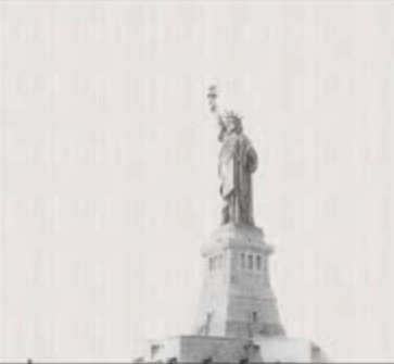 A white wall built in scale from one day of USA paper cups with two people (dots at lower left) and Statue of Liberty; click to see a great TED video